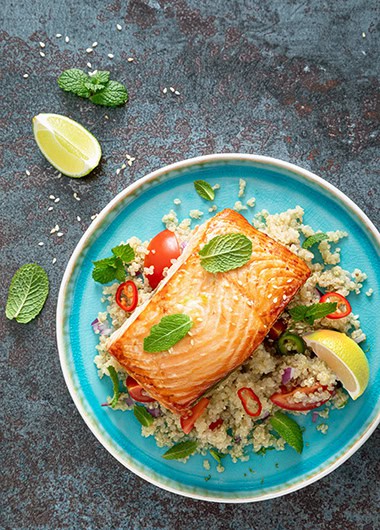Grilled salmon fillet, quinoa fresh vegetable salad with tomato and avocado guacamole. Top view